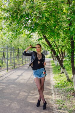 Çekici bir kadın portresi bahar kuş-kiraz ağacı çiçek altında yolda bekleyen bir deri ceket giymiş