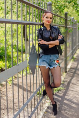 Eski bir metal çit yanında bir deri ceket durduğunu kadında