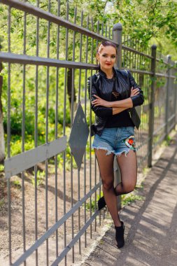 Eski bir metal çit yanında bir deri ceket durduğunu kadında