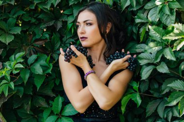 Siyah üzüm ile siyah elbiseli genç seksi esmer portresi. .