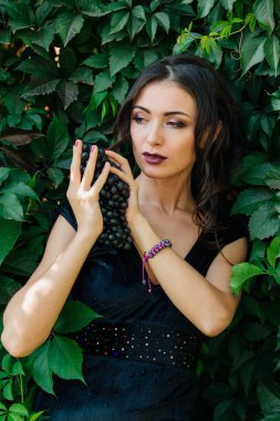 Siyah üzüm ile siyah elbiseli genç seksi esmer portresi. .