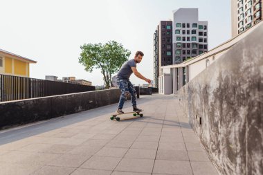 Sokakta longboard sürme sakallı genç yakışıklı adam.