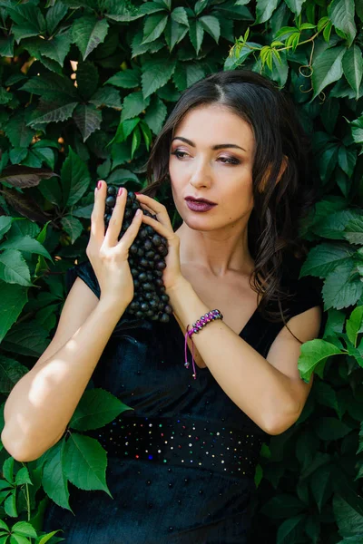 Siyah üzüm ile siyah elbiseli genç seksi esmer portresi. .