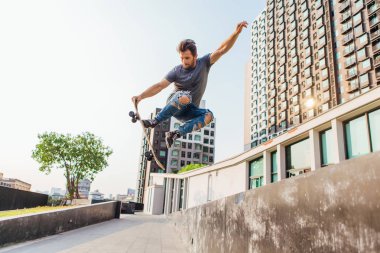 Yüksek atlama ve hile yaparak bir kaykay üzerinde genç adam