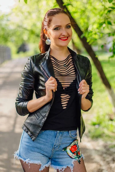 Charmante vrouw gekleed in een lederen jas staande op de weg — Stockfoto