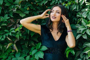 Siyah üzüm bir küpe gibi tutarak siyah elbiseli Genç Seksi esmer portresi.