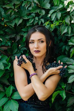 Siyah üzüm ile siyah elbiseli genç seksi esmer portresi. .