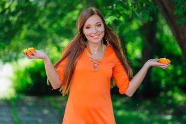 Yaz yeşil Parkı'nda tamamlayan bir sulu lezzetli portakal tutan güzel kızıl saçlı kadın portresi.