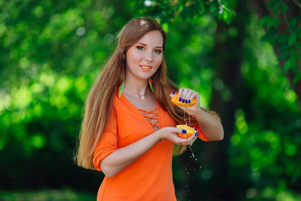 공원에서 오렌지의 반쪽을 손으로 누르면 여자의 초상화 — 스톡 사진