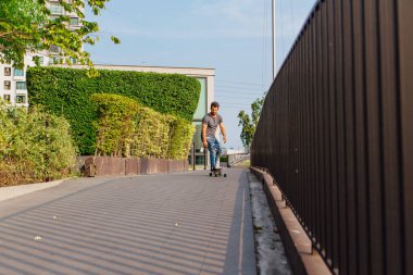 Sokakta longboard sürme sakallı genç yakışıklı adam.