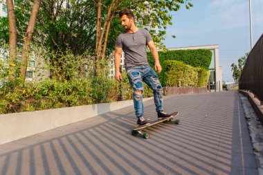 Sokakta longboard sürme sakallı genç yakışıklı adam.