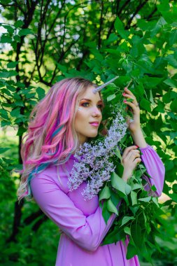 Gökkuşağı saç ve parlak makyaj Lila çiçek tutan olan peri kız at.