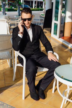 Yakışıklı işadamı bir kafede kahve molası sırasında telefonda konuşurken