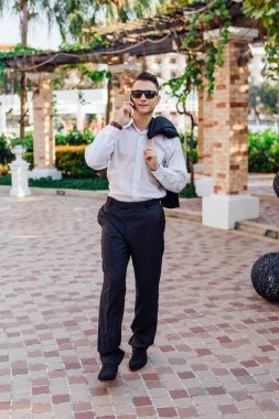 Genç işadamı telefonunu açık havada tropikal bir ülkede konuşurken