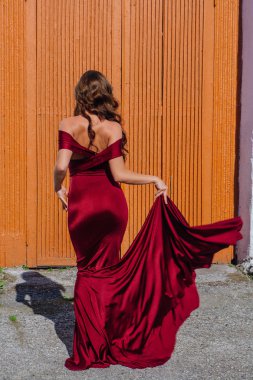 Arkadan görünüş eski kapı yanındaki bir tren konumu olan bir uzun kırmızı gece elbisesi içinde güzel bir genç kadın