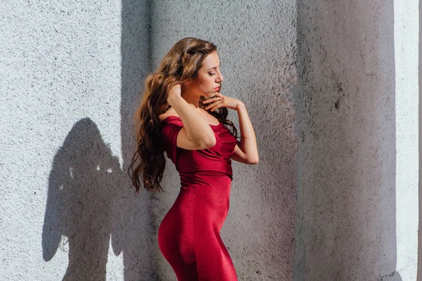 Güzel genç kadın yanındaki duvar eski bir tren konumu olan bir uzun kırmızı gece elbisesi