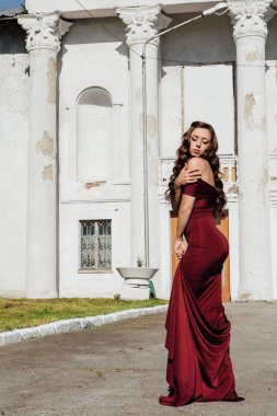 Güzel genç kadın yanındaki duvar eski bir tren konumu olan bir uzun kırmızı gece elbisesi