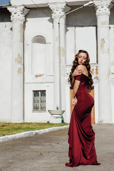 Güzel genç kadın yanındaki duvar eski bir tren konumu olan bir uzun kırmızı gece elbisesi