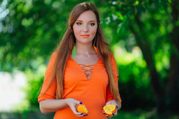 Yaz yeşil Parkı'nda tamamlayan bir sulu lezzetli portakal tutan güzel kızıl saçlı kadın portresi.