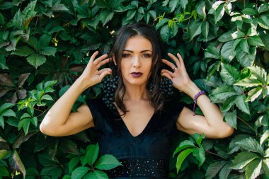 Siyah üzüm bir küpe gibi tutarak siyah elbiseli Genç Seksi esmer portresi.