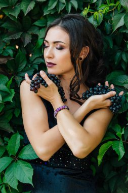Siyah üzüm ile siyah elbiseli genç seksi esmer portresi. .