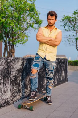 Genç yakışıklı adamla sokakta longboard ile sakal ayakta.