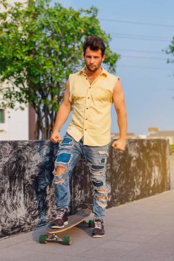 Genç yakışıklı adamla sokakta longboard ile sakal ayakta.