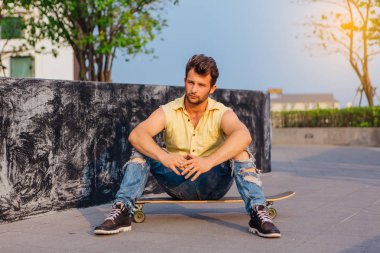 Sakallı longboard sokakta oturan genç yakışıklı adam.