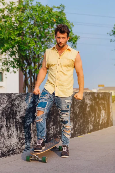 Genç yakışıklı adamla sokakta longboard ile sakal ayakta.