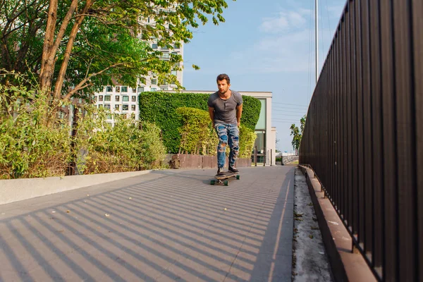 Sokakta longboard sürme sakallı genç yakışıklı adam.