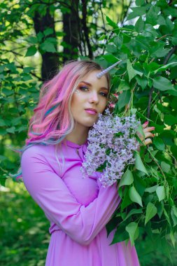 Gökkuşağı saç ve parlak makyaj Lila çiçek tutan olan peri kız at.