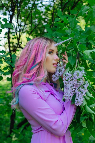 Gökkuşağı saç ve parlak makyaj Lila çiçek tutan olan peri kız at.