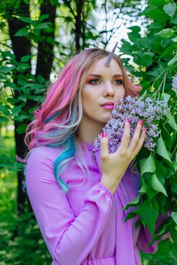 Gökkuşağı saç ve parlak makyaj Lila çiçek tutan olan peri kız at.