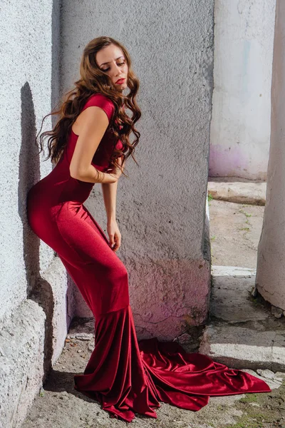 Güzel genç kadın yanındaki duvar eski bir tren konumu olan bir uzun kırmızı gece elbisesi