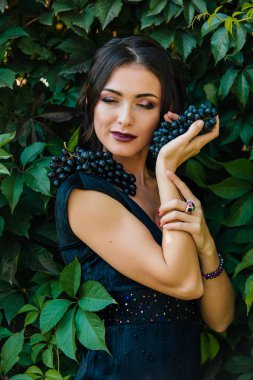 Siyah üzüm ile siyah elbiseli genç seksi esmer portresi. .