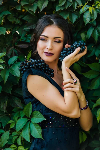 Siyah üzüm ile siyah elbiseli genç seksi esmer portresi. .