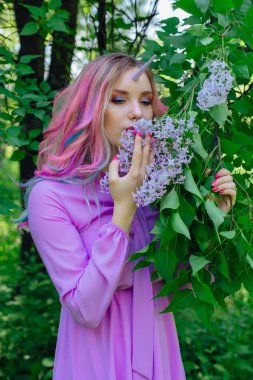 Gökkuşağı saç ve parlak makyaj Lila çiçek tutan olan peri kız at.