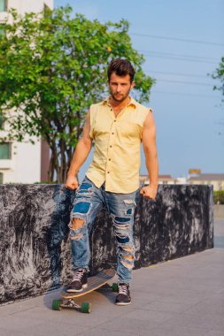 Genç yakışıklı adamla sokakta longboard ile sakal ayakta.