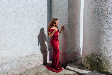 Güzel genç kadın yanındaki duvar eski bir tren konumu olan bir uzun kırmızı gece elbisesi