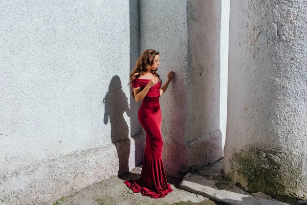 Güzel genç kadın yanındaki duvar eski bir tren konumu olan bir uzun kırmızı gece elbisesi