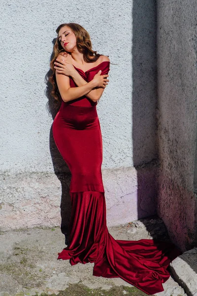 Güzel genç kadın yanındaki duvar eski bir tren konumu olan bir uzun kırmızı gece elbisesi