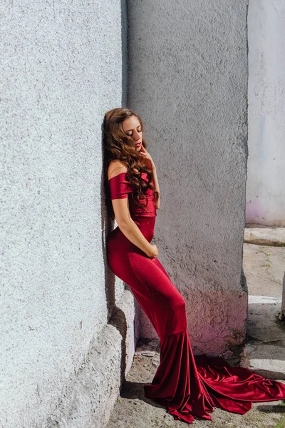 Hermosa mujer joven en un vestido de noche largo rojo con un tren — Foto de Stock