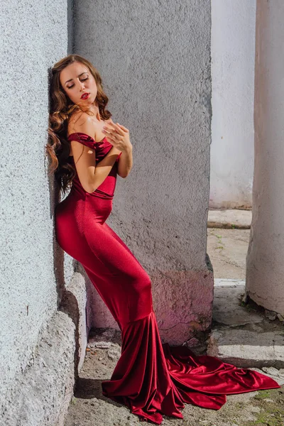 Hermosa mujer joven en un vestido de noche largo rojo con un tren — Foto de Stock