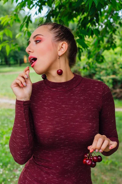 Hermosa mujer joven con trenza larga y pendientes de cereza natural . — Foto de Stock