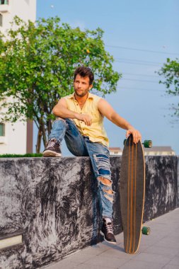 İle longboard sokakta oturan genç adam.