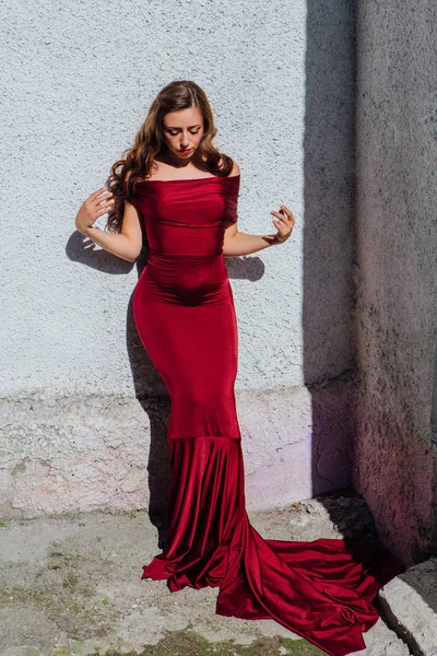 Güzel genç kadın yanındaki duvar eski bir tren konumu olan bir uzun kırmızı gece elbisesi