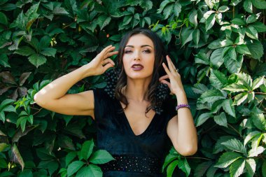 Siyah üzüm bir küpe gibi tutarak siyah elbiseli Genç Seksi esmer portresi.