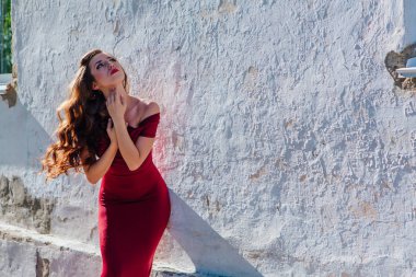 Uzun kırmızı gece elbisesi ayakta duvar eski yanında güzel ve genç birbayan. Kopya alanı.