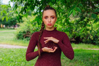 Kiraz elinde tutan uzun örgü ve kiraz küpe olan güzel kadın