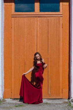 Eski kapı yanındaki bir tren konumu olan bir uzun kırmızı gece elbisesi güzel genç kadın